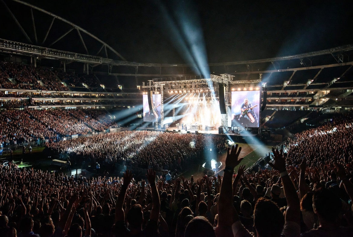 Epic stadium concert with massive crowd and dramatic stage lighting